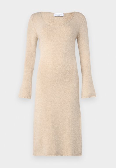 Bežs adīts kleita ar garām izplestām piedurknēm, apaļu kakla izgriezumu un mīkstu tekstūru; krīt tieši virs ceļgaliem ar apstrādātām malām.