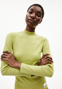 Langsleeve ribbed top in lichtgroen, met een hoge hals en een getailleerde pasvorm. Inclusief een klein merkembleem aan de zijkant.