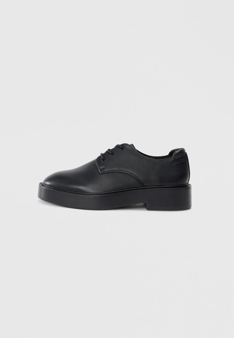 Pantofi din piele neagră, cu șireturi, vârful rotunjit, talpa groasă neagră și un design minimalist. Textură netedă, fără modele sau accente vizibile.