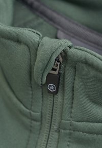 Tessuto di felpa verde con chiusura a zip, caratterizzato da una finitura testurizzata e un piccolo logo nero sul cursore della zip.