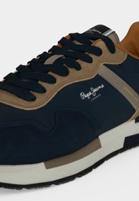 Basket bleu marine et beige avec lacets noirs, semelle blanche et logo "Pepe Jeans London" sur le côté et la languette.