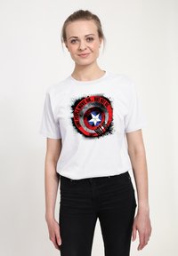 Hvid bomulds T-shirt med et grafisk design af en stjerne i en rød og sort cirkel, teksten lyder "Nogle mennesker går videre... men ikke os."