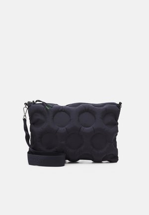 Rektangulær sort polstret skuldertaske med cirkulære syede mønstre, lynlåslukning og justerbar strop af stof med metalhægte.