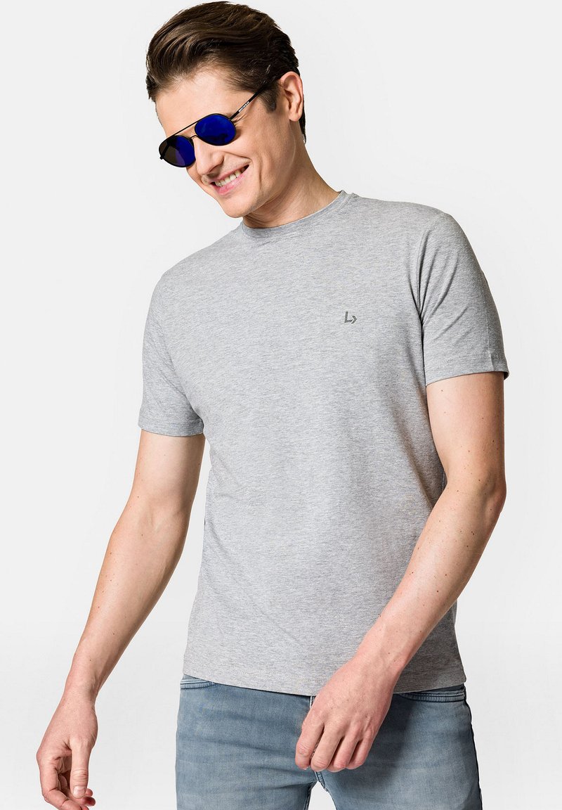 Szara krótka koszulka z krótkim rękawem o miękkiej fakturze, okrągły dekolt, z małym logo na piersi. Połączona z niebieskimi okularami przeciwsłonecznymi.