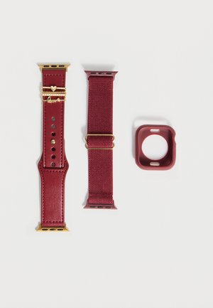 Zwei rote Apple Watch Armbänder – eines aus Leder mit goldenem Herz und Liebesanhängern, eines aus Stoff mit goldener Schnalle – und ein passendes rotes Uhrengehäuse.