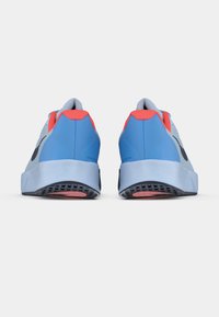 Adidași bleu deschis cu plasă gri și accente roșii, având o talpă texturată, o formă rotunjită și detalii negre pe călcâi și pe laturi.