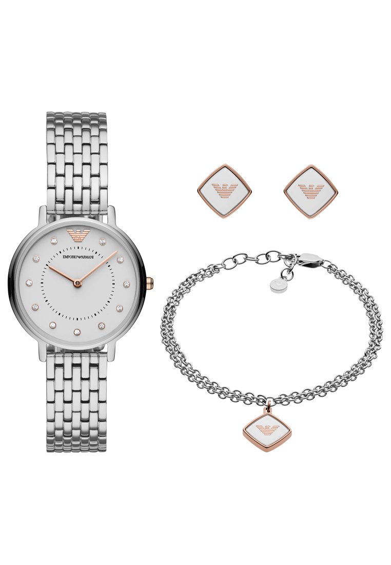 Srebrny zegarek ze stali nierdzewnej z białą tarczą, zdobionymi znacznikami i różowozłotymi akcentami. W zestawie bransoletka i kolczyki z logo.