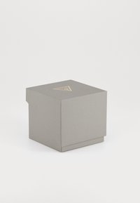 Grå teksturert boks med et trekantet gullmerke på toppen, firkantet form og subtile linjer på overflaten, designet for presentasjon.