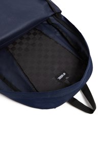 Zaino blu navy con un'esterno testurizzato, chiusura con zip e rivestimento a motivo quadretti. Include un'etichetta del marchio visibile all'interno.