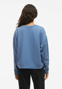 Blå sweatshirt med avslappnad passform, lång ärm och rundad halsringning. Mjuk tyg med slät textur och ribbad nederkant.