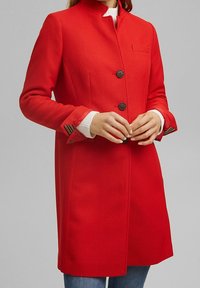 Rode jas met een gestructureerd ontwerp, voorzien van een hoge kraag, drieknoopssluiting en gestreepte accenten op de manchetten. Geweven stof.