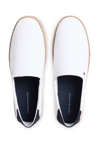 Λευκά πάνινα παπούτσια χωρίς κορδόνια με φυσική σόλα από σχοινί, διαθέτουν σκούρο μπλε εσωτερικό και μικρή λογότυπη λεπτομέρεια σε κόκκινο και μπλε στο πλάι.