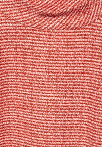 Tessuto rosso testurizzato con un motivo intrecciato, caratterizzato da fili chiari e scuri alternati che creano un effetto a strisce.