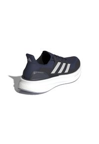 Zapatilla de running en color azul marino con parte superior de tejido de punto, tres franjas reflectantes blancas, entresuela blanca acolchada y suela texturizada.