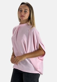 Hellrosa, übergroße Bluse mit hohem Kragen und kurzen, weiten Ärmeln. Strukturierter Stoff mit dezenten Falten und einem lockeren Schnitt.