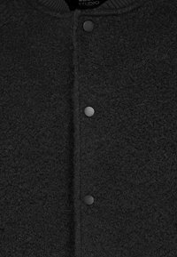 Black, textured jacket with a fleece-like material, featuring a ribbed collar and black snap buttons along the front.