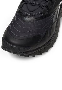 Čierna športová obuv s textúrovaným vrchným materiálom a vlnovitými vzorovými akcentmi. Odolná gumová podrážka s výraznými trakčnými výstupkami.