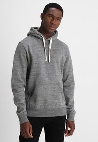 Sudadera gris hecha de una tela suave, con un bolsillo frontal, capucha con cordón y puños acanalados. Diseño simple y relajado.