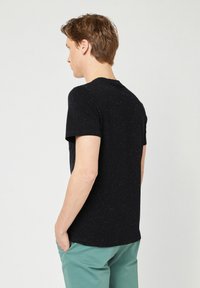 Schwarzes T-Shirt mit kurzen Ärmeln und gesprenkeltem Muster, aus weichem Stoff gefertigt. Die Rückseite verfügt über ein klassisches Rundhalsdesign.