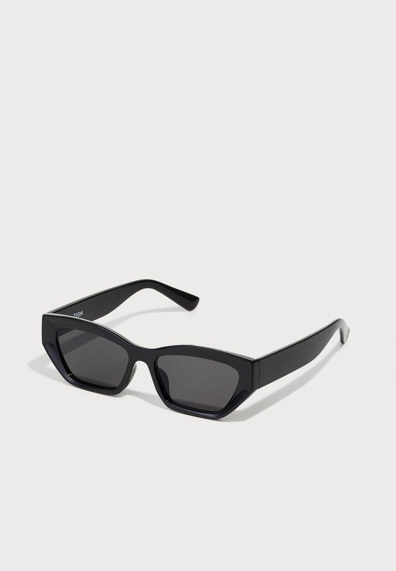 Óculos de sol retangulares pretos com armações grossas, lentes escuras e design angular. Material plástico liso sem padrões ou detalhes visíveis.