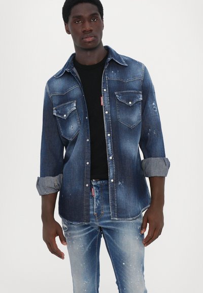 Denim shirt in dark blue with faded accents and light blue sleeve cuffs. Pair with matching distressed jeans. Features two chest pockets.