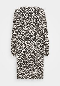 Pitkähihaisessa mustassa mekossa on satunnaisia valkoisia abstrakteja lehtikuvioita ja joustavat hihansuut, taustalla on yksinkertainen tausta.