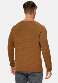 Brun tekstureret sweater med lange ærmer og et ribbet mønster, med en rund hals og en let tilpasset silhuet set fra bagsiden.