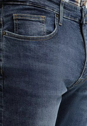 Jeans dżinsowe w ciemnoniebieskim kolorze z klasycznym pięciopocketowym fasonem. Posiadają widoczne przeszycia, subtelną teksturę oraz standardowy pas.
