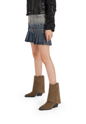 Stivaletti in suede marrone con tacco leggero, caratterizzati da un design ripiegato e una texture liscia. Abbinati a una gonna di jeans e una giacca di pelle.