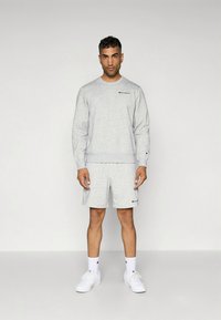 Gråt bomuldsæt med sweatshirt og shorts, med ribkanter, logo-broderi og matchende hvide sneakers med sokker. Minimalistisk design.