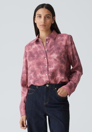 Lichtroze overhemd met een tie-dye patroon, lange mouwen en een klassieke kraag, gecombineerd met donkerblauwe spijkerbroeken.