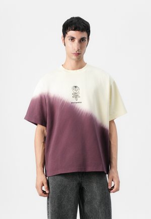 Bomull T-skjorte med en gradientdesign fra kremfarge til burgunder, med en blomsterillustrasjon og logo sentrert under halsen.