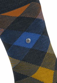 Chaussette à motifs avec un fond sombre ornée de diamants en bleu, orange et jaune, mettant en valeur un bouton métallique sur le design.