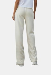 Sweatpants in crèmekleurige, zachte stof, met een losse pasvorm, elastische tailleband en rechte pijpen, voor comfort en bewegingsvrijheid.