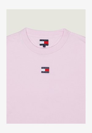 T-shirt rose clair à col rond avec un petit patch logo Tommy Jeans centré sur la poitrine et une étiquette à l'intérieur du col. Taille XS.