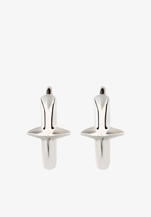 Paire de boucles d'oreilles créoles en forme de croix en argent poli, avec des surfaces lisses et des bords arrondis sur fond blanc.