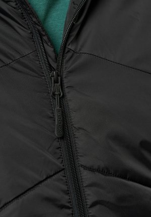 Zwarte gewatteerde jas met een ritssluiting aan de voorkant en een gequiltde textuur. De rits heeft een 'Kappa' merklogo. Een groene kledingstuk is zichtbaar eronder.