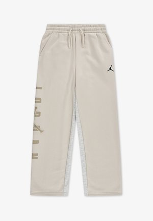 Beige jogger pants with an elastic waistband, two side pockets, and a black Jordan logo. Features side paneling in light gray.