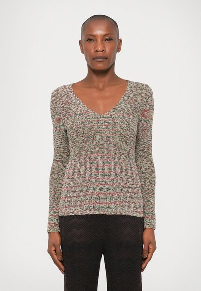 Pull en tricot multicolore avec un col en V, des manches longues et un motif texturé. Associé à un pantalon noir à motif zigzag.
