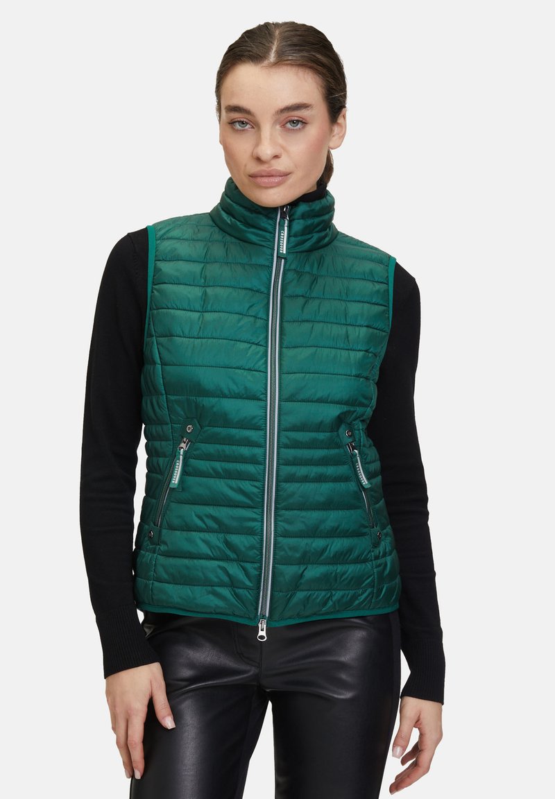 Grön vadderad väst med hög krage, framzip, och två fickor med dragkedja. Slät textur, horisontellt kviltat mönster, lättviktsdesign.