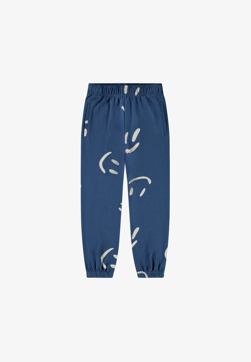 Blue cotton jogger pants with elastic waistband, featuring abstract white smiley designs and side pockets. Elastic cuffs at ankles.