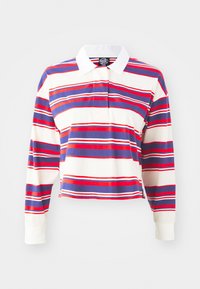 Langermet polo skjorte i kremfarge med horisontale striper i blått, rødt og hvitt. Har hvit krage og cropped design. Mykt stoff.