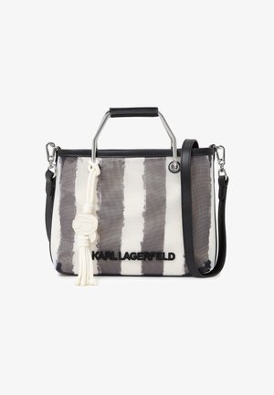 Pravokutna torba za nošenje s okomitim sivim i bijelim prugama, crnim obrubom, metalnim ručkama, odvojivim crnim remenom i bijelim privjeskom s resicama.