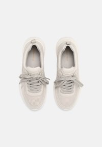 Baskets gris clair avec une tige en mesh texturé, une semelle épaisse et des lacets plats ; logo visible sur la semelle intérieure.