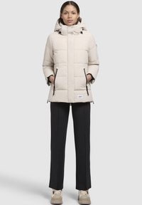 Helle beige Daunenjacke mit Kapuze, versehen mit einem quadratischen Steppmuster, mit Reißverschlusstaschen an den Seiten und einem Logopatch auf der Vorderseite.