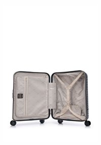 Valigia rigida nera, con interno beige dotato di tasca con zip, cinghie elastiche e motivo trapuntato sulla fodera.