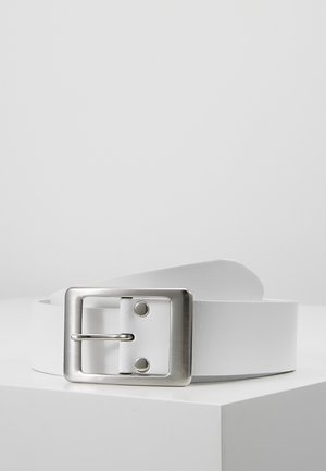 Ceinture en cuir blanc avec une boucle rectangulaire en métal argenté placée sur une surface blanche sur un fond uni.