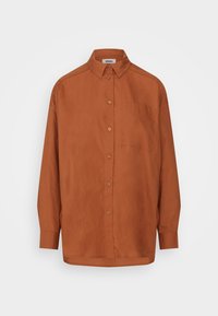 Camisa castanha com botões, colarinho aberto, mangas longas, um único bolso no peito e textura de tecido suave.