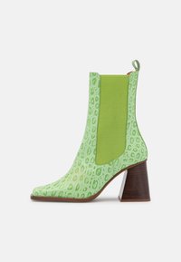Botín verde con patrón de cocodrilo texturizado, paneles laterales elásticos y un chunky tacón de madera. Diseño de punta afilada.