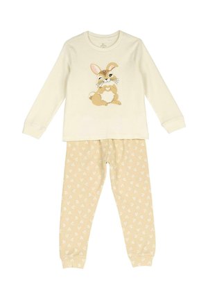 Haut crème à manches longues avec un lapin de dessin animé faisant un clin d'œil en formant un cœur, associé à un pantalon beige couvert de petits cœurs blancs.